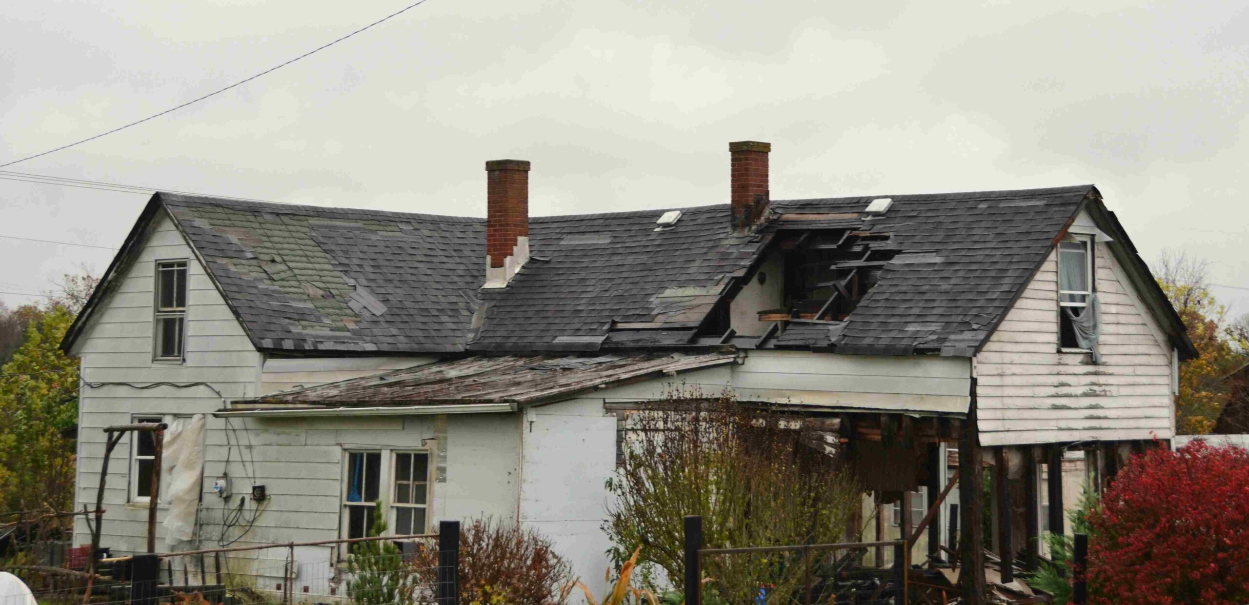 Storm-damaged roof with missing and damaged shingles on a home