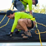 Roofers performing roof repair work on asphalt shingles